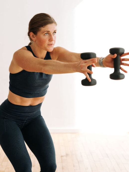 woman performing a dumbbell press out in a barre workout