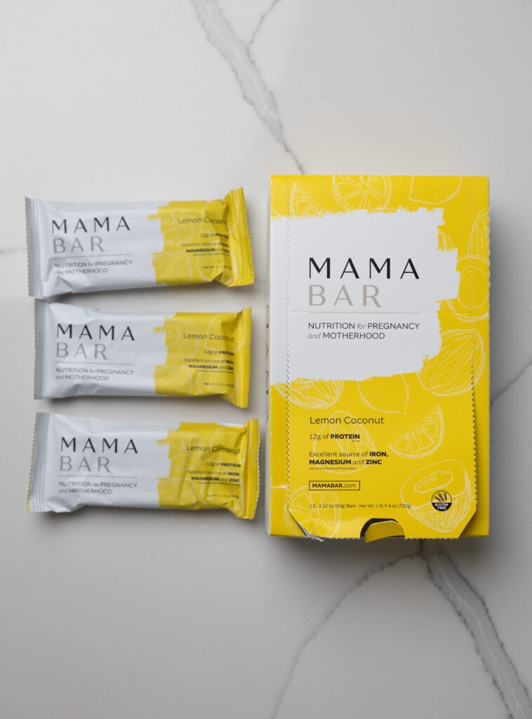 Box of mama bars and three protein bars to the left in the flavor lemon coconut.