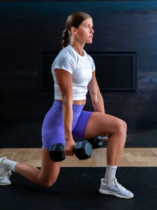 woman performing a reverse lunge with dumbbells in a leg workout
