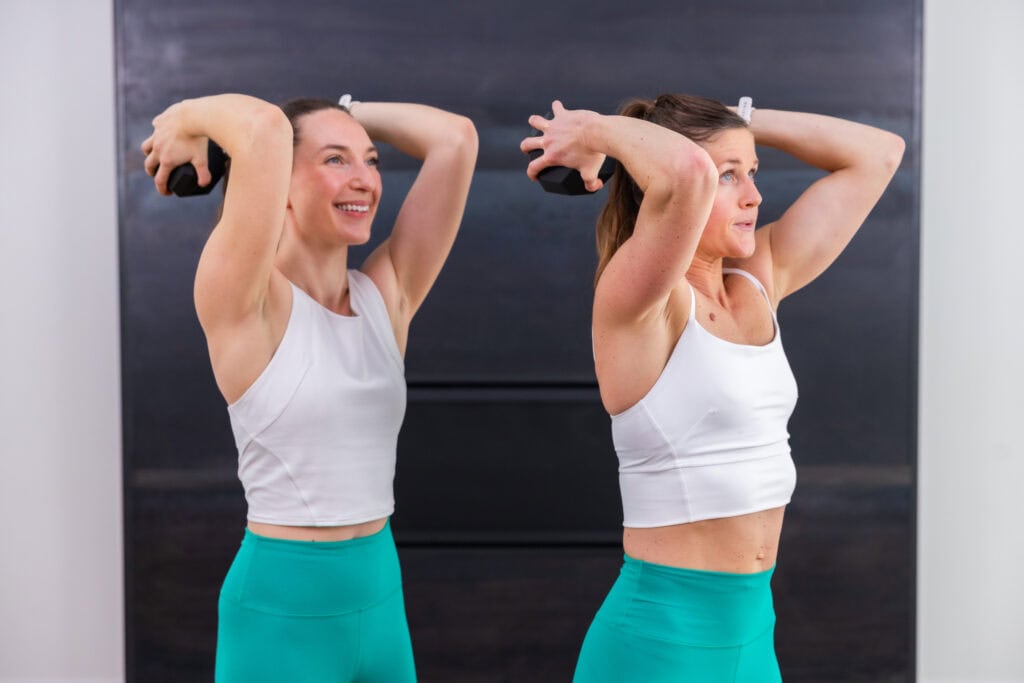 two women performing an overhead tricep extension with a single dumbbell in a chest and tricep workout