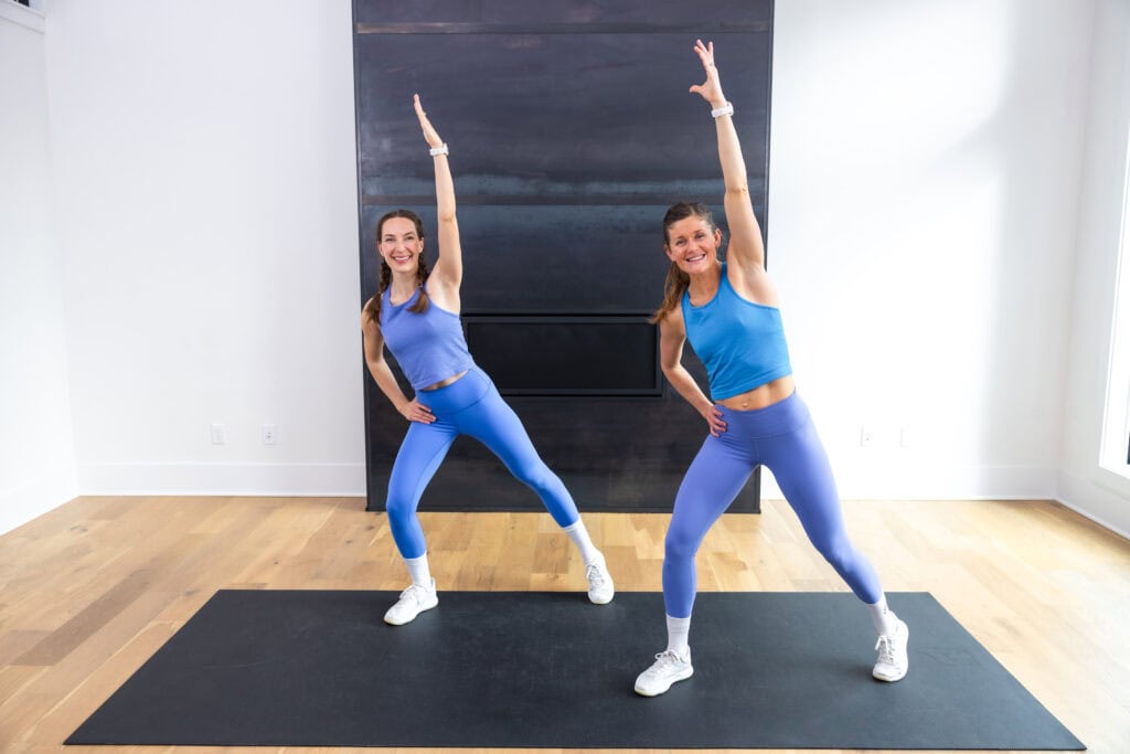 two women performing standing ab exercise as part of at home cardio workout