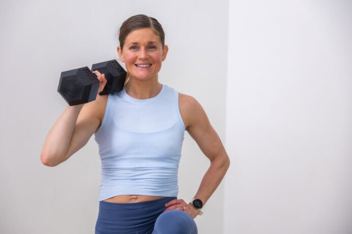 Woman performing low impact cardio high knees holding a dumbbell