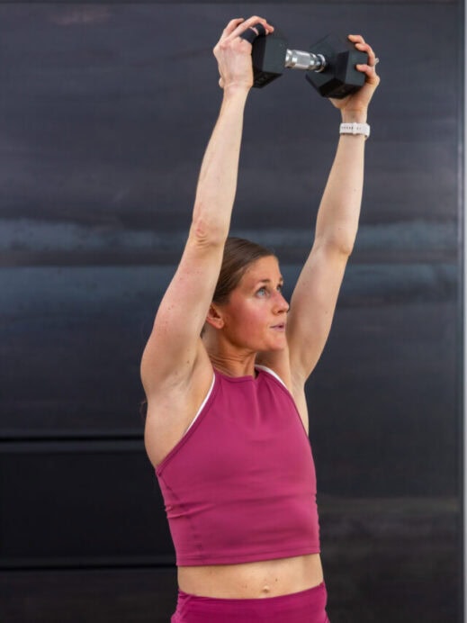 woman performing a diagonal chop as part of core training with dumbbells