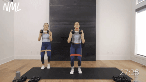 two women performing lateral steps with a shoulder press as part of LISS cardio workout