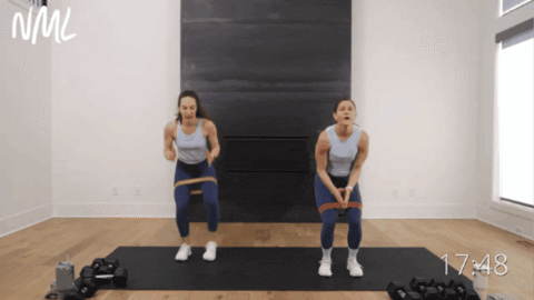two women performing loaded squat jacks as example of LISS cardio exercise