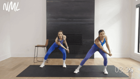 two women performing a crossbody chop as example of standing pilates abs exercises