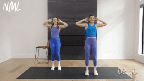 two women performing standing bicycle crunches as part of pilates ab workout