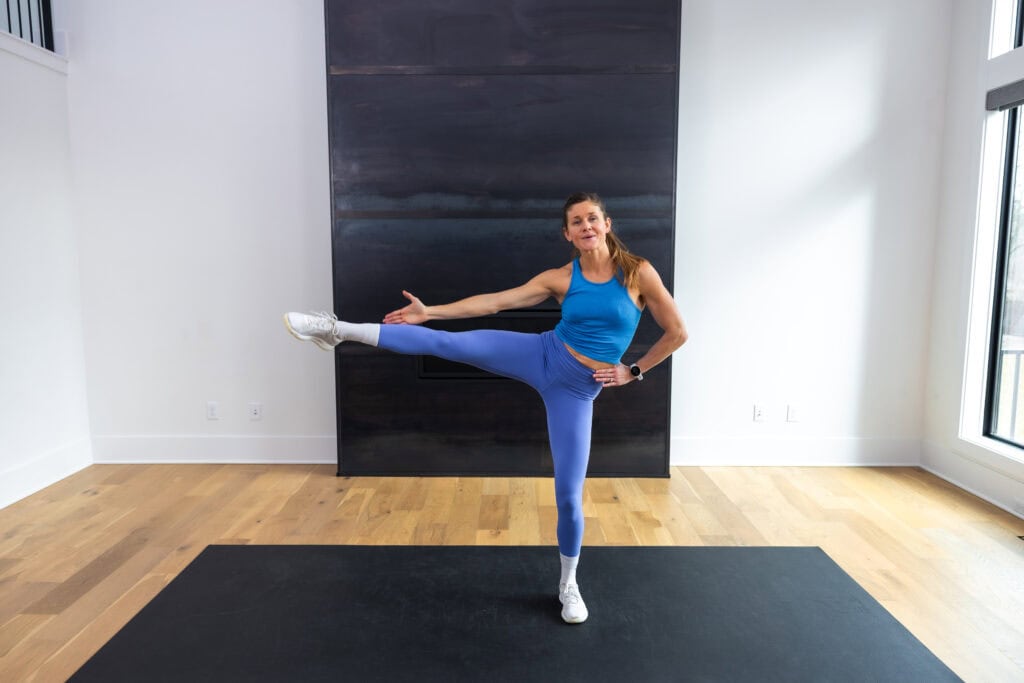 woman performing a standing leg lift as part of pilates ab workout