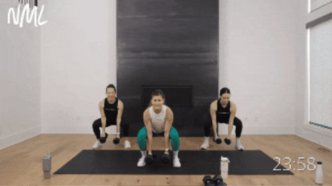 three women performing a squat variation as part of dumbbell only workout