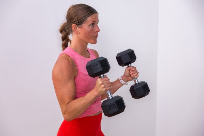 woman performing a bicep curl hold with dumbbells in a full body home workout