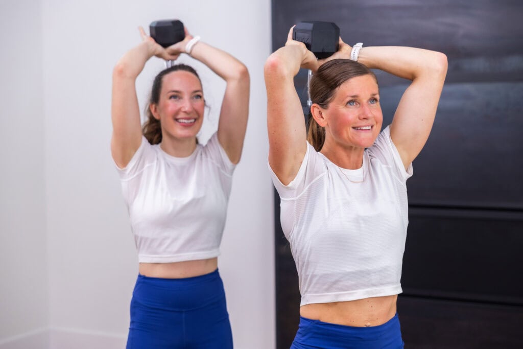 women performing overhead tricep extensions 