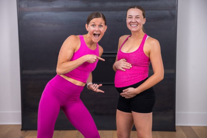 one woman pointing to another woman's pregnant belly as part of prenatal workout